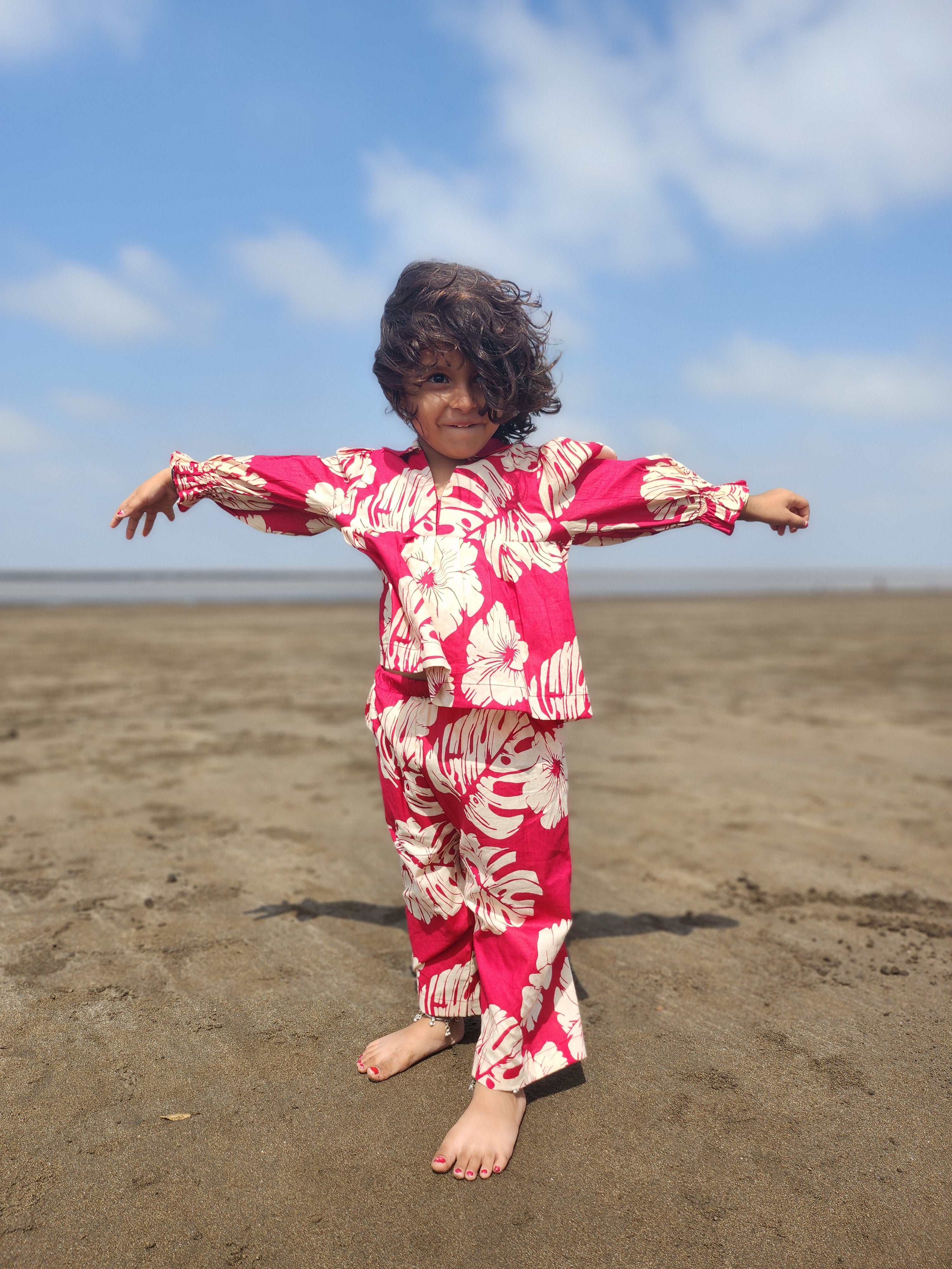 Baby girl wearing red tropical floral co-ord set on beach