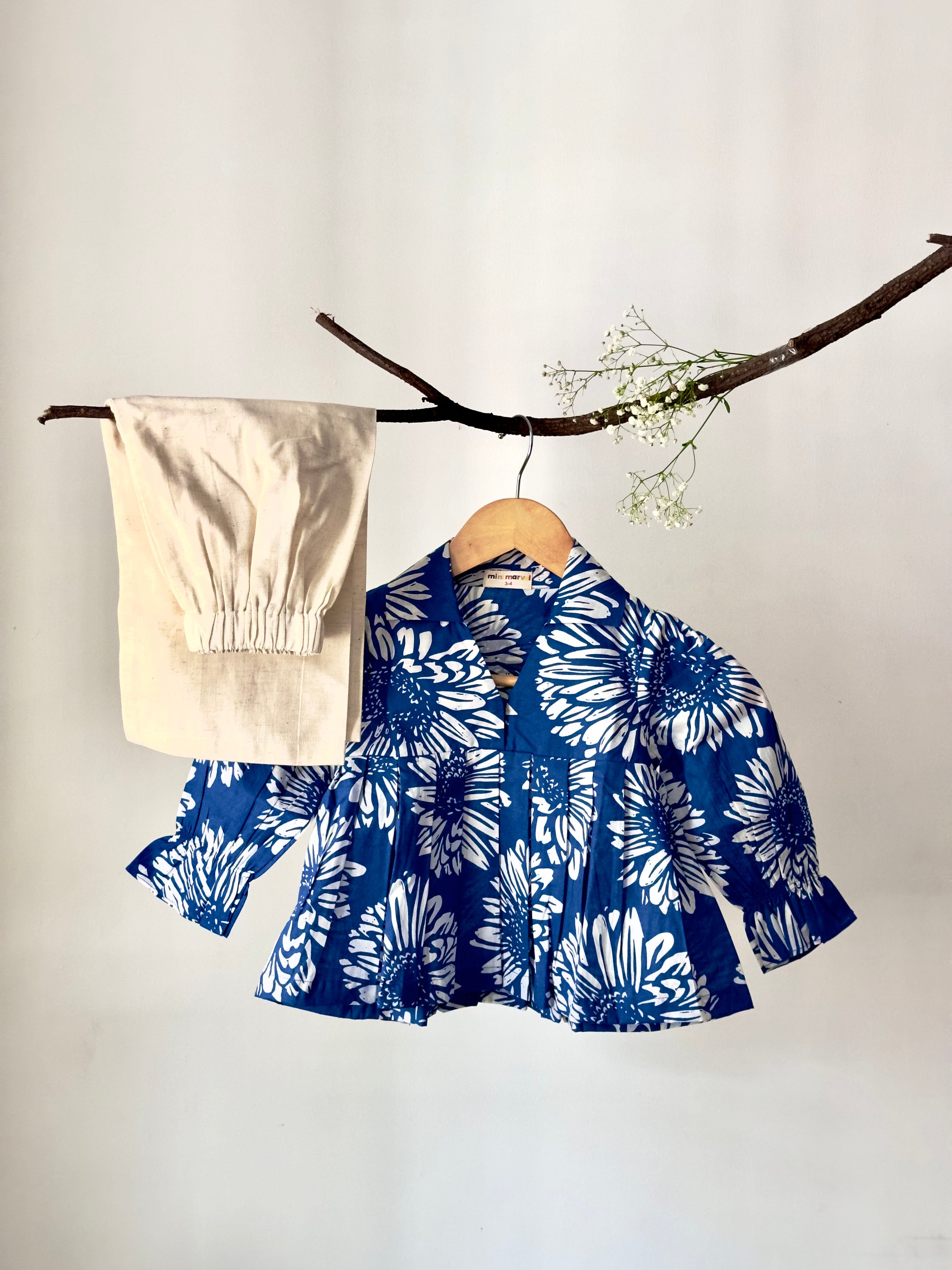 Blue floral dress with beige pants on a wooden hanger against a white background
Baby girl outfit set with comfy elastic-waist bloomers