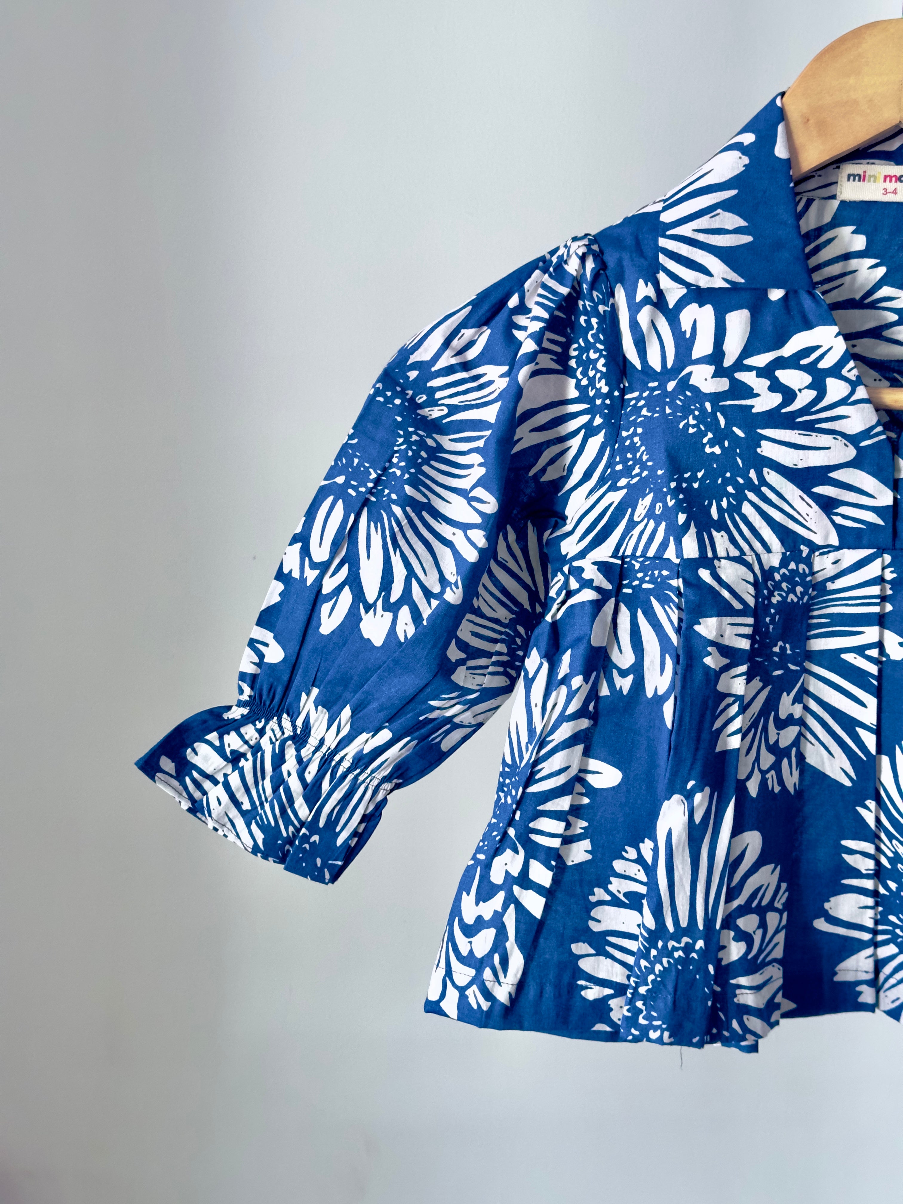 Blue floral patterned dress on a wooden hanger against a gray
background
Baby girl matching outfit set in blue and cream